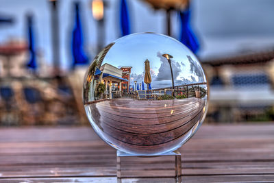 Close-up of crystal ball on glass table against buildings in city