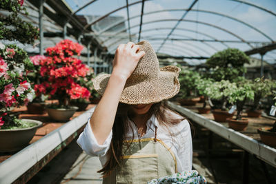 Woman wearing hat while standing against plants