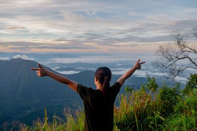 Rear view of man with arms raised against sky