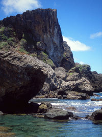 Rock formation by sea against sky