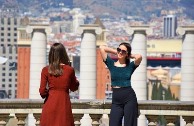 Full length of woman standing by railing against buildings in city