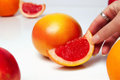 Female hand holding piece of a red grapefruit on white background. healthy food concept. fresh 