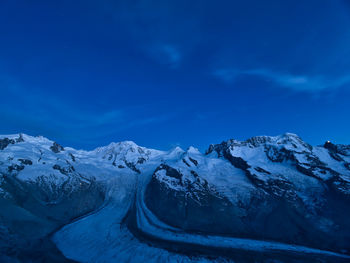 Snow covered mountains against blue sky