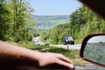 Cars on road by trees against sky seen through car windshield