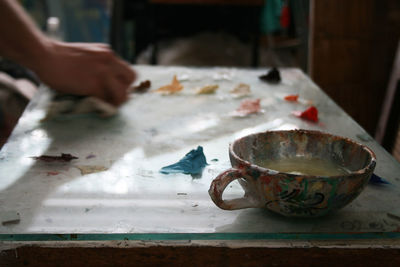 Cropped hand of painter working in studio with focus on cup