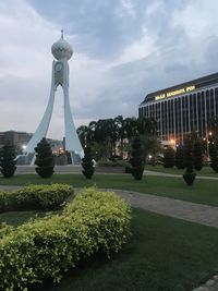 Statue in city against cloudy sky