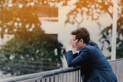 Side view of young man standing by railing