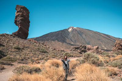 Woman standing on mountain against clear blue sky