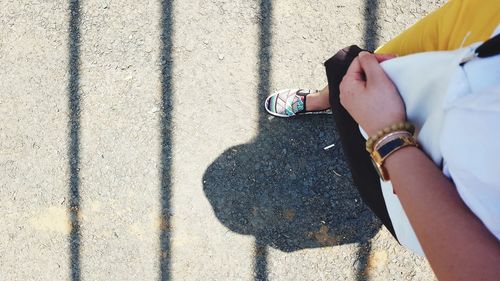 Low section of woman walking on road during sunny day