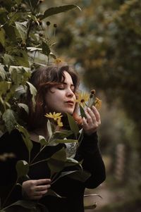 Close-up of young woman holding flowering plant outdoors