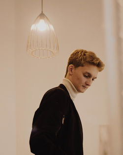 Side view of young man looking away against wall