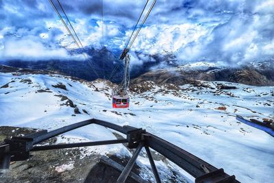 Ski lift over snow covered mountains against sky