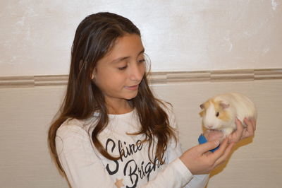 Close-up of girl holding hamster at home