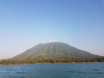 Scenic view of sea and mountains against clear blue sky