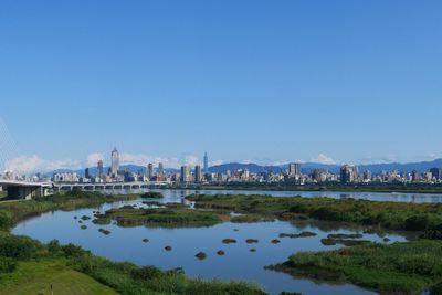 City at waterfront against blue sky