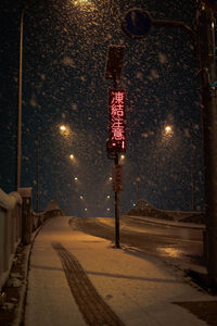 Illuminated street light on road in city at night