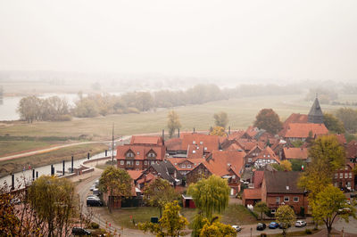 Houses on field by buildings against sky