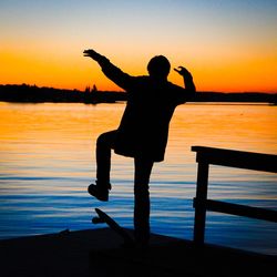 Silhouette of people standing on beach at sunset