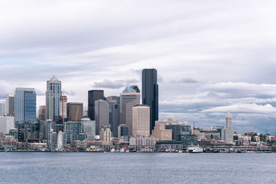 Sea by buildings against sky in city