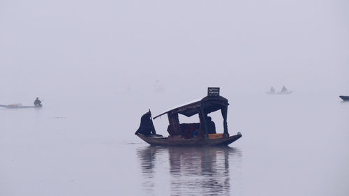 People in boat on lake against sky