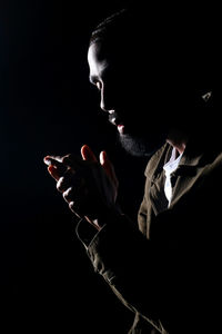 Full length portrait of young man holding cigarette against black background