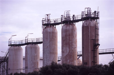 Low angle view of oil tanks against the sky