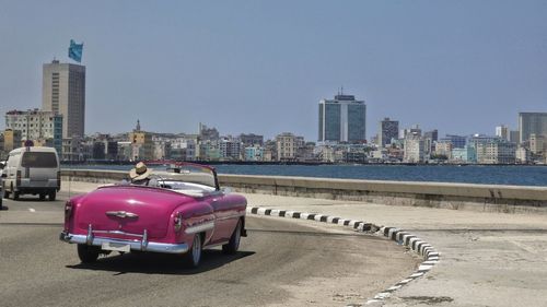 Cityview to skyline of havana with pink oldtimer on malecon