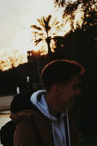 Boy in park against sky during sunset