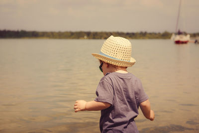 Boy wearing hat while standing at beach 