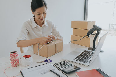 Young woman using phone while sitting on table