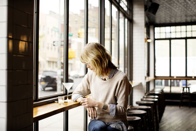 Rear view of woman using mobile phone at home