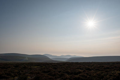 Scenic view of landscape against bright sun