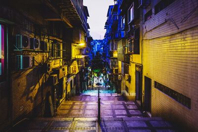 Narrow alley amidst buildings in city at night