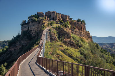 Tourist walking on bridge by castle against clear blue sky