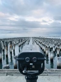 Panoramic view of wooden posts in sea against sky