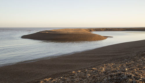 Scenic view of beach against clear sky during sunset