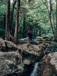 Standing man taking photos on rock in the forest