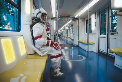 Full length of astronaut sitting on subway train