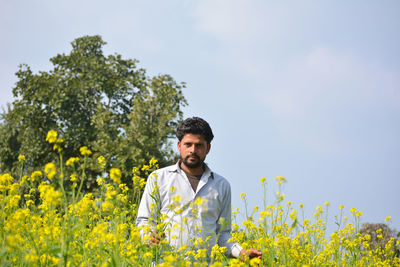 Young man with yellow flowers in field