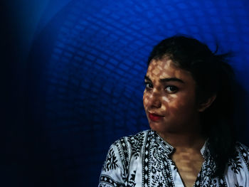 Close-up portrait of young woman against black background