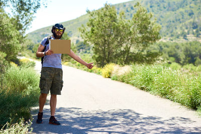 Man gesturing thumbs up while standing on road amidst plants