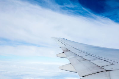 Cropped image of airplane flying against cloudy sky