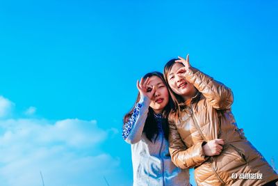 Portrait of smiling young woman against blue sky