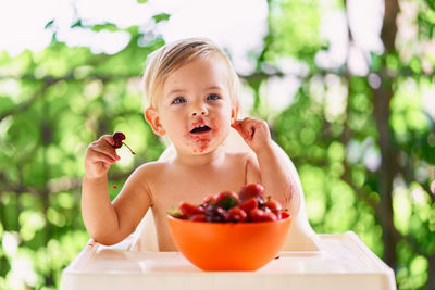 Portrait of shirtless boy eating fruit