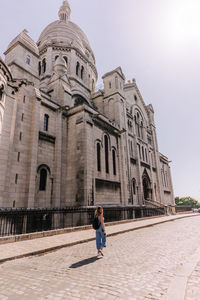 Woman outside temple against sky in city