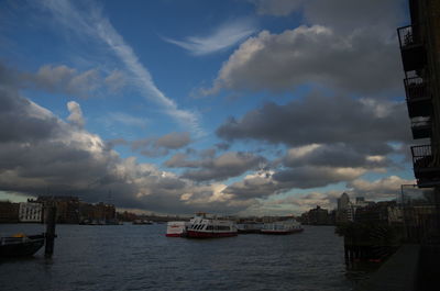 Boat in river against cloudy sky