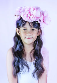 Portrait of smiling girl standing against pink background