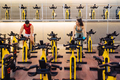 Front view of a couple in love doing cardio bike in modern gym