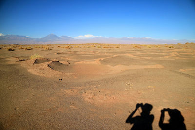Shadow of two tourists on the ground of aldea de tulor ancient village, san pedro de atacama, chile