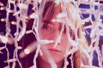 Close-up portrait of young woman with illuminated fairy lights